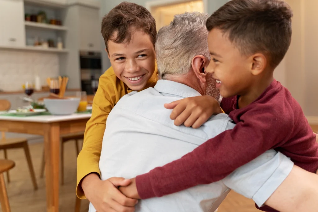 2 children hugging a elderly man