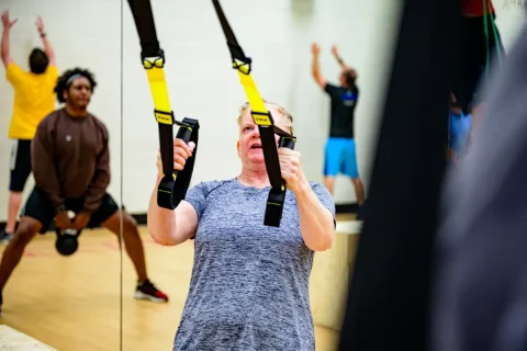 Group of people in gym doing various kinds of strength training.